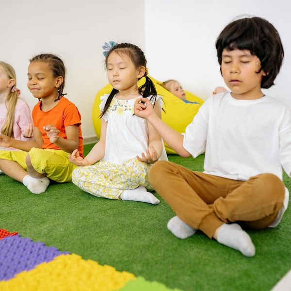 Group of diverse kids laughing during a yoga class.